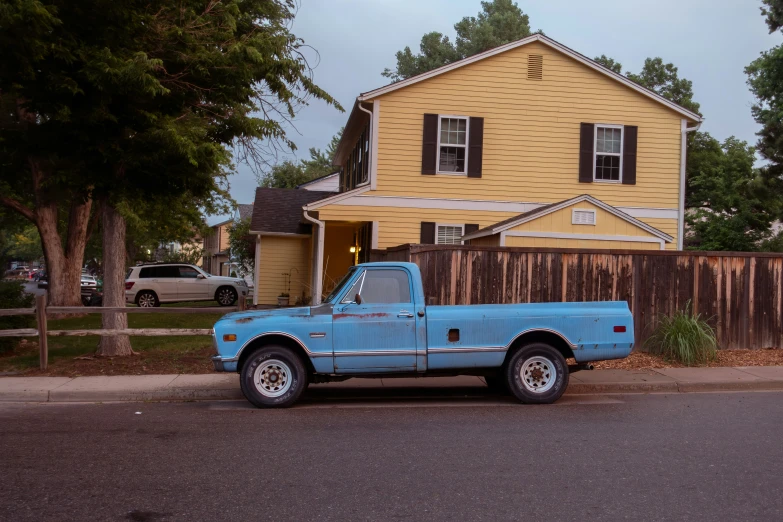 blue truck parked on the curb outside a house