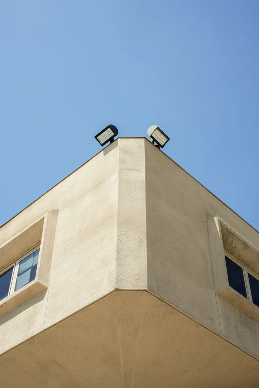 two security cameras sit atop a large building