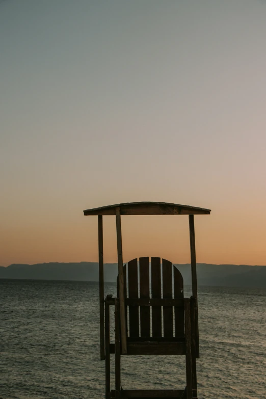 a chair with its umbrella up next to the water