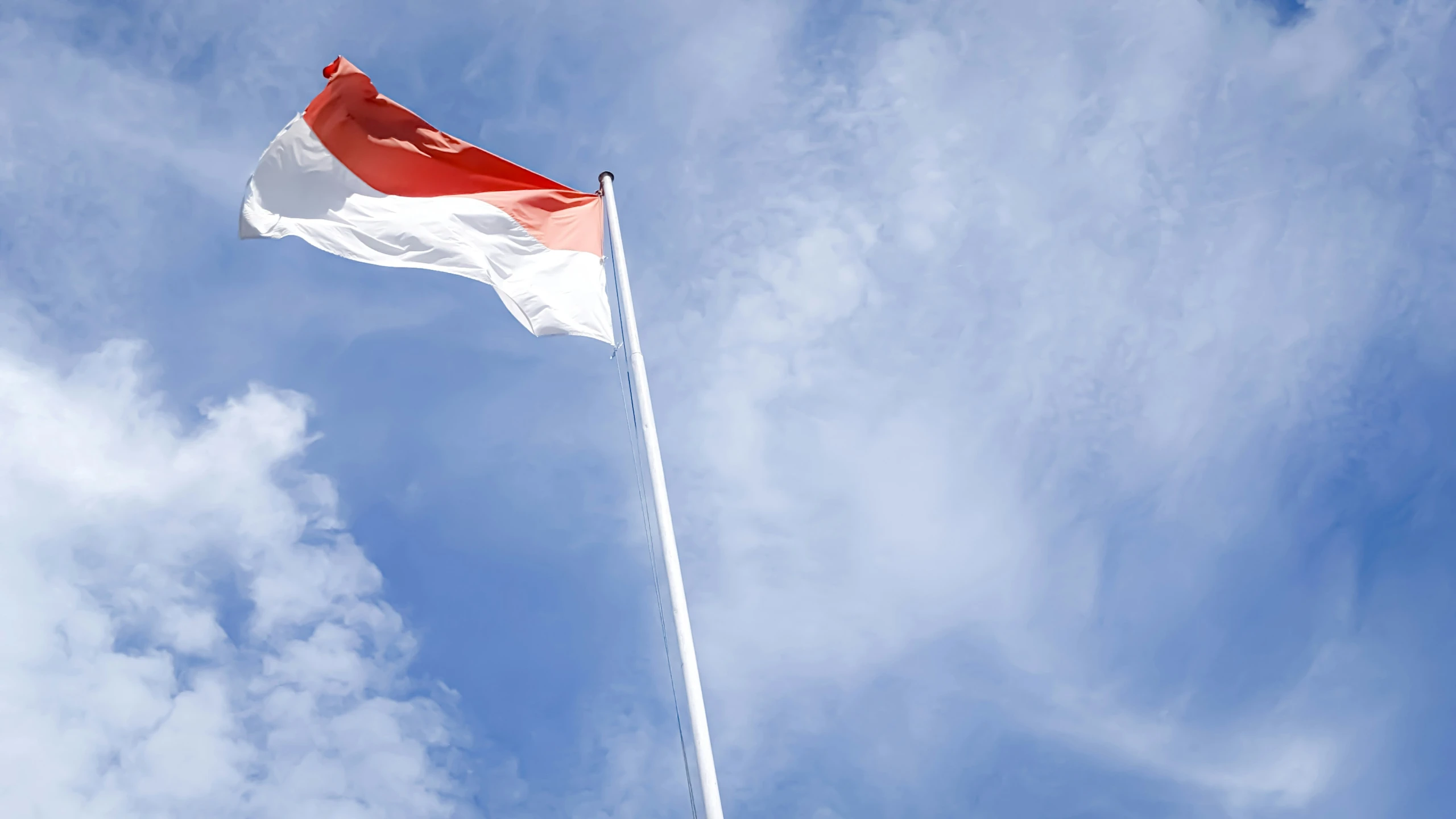 an air plane with red and white on top flying in the sky