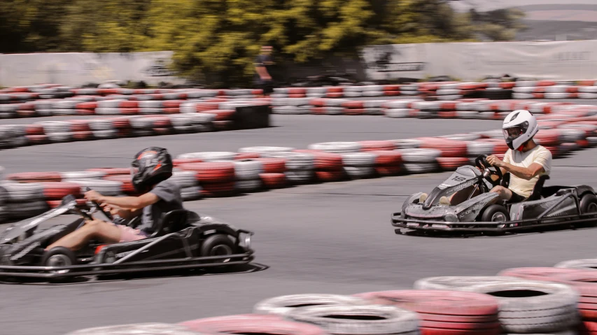 two people are riding on go karts in a racing track