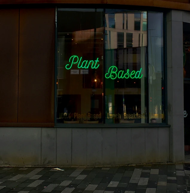 a store front with the sign plant based in green