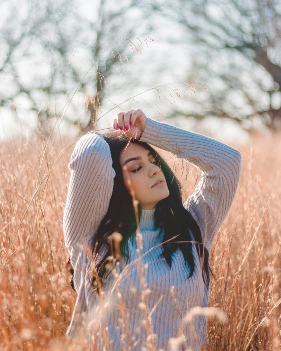 the woman in the field is standing and stretching her hair