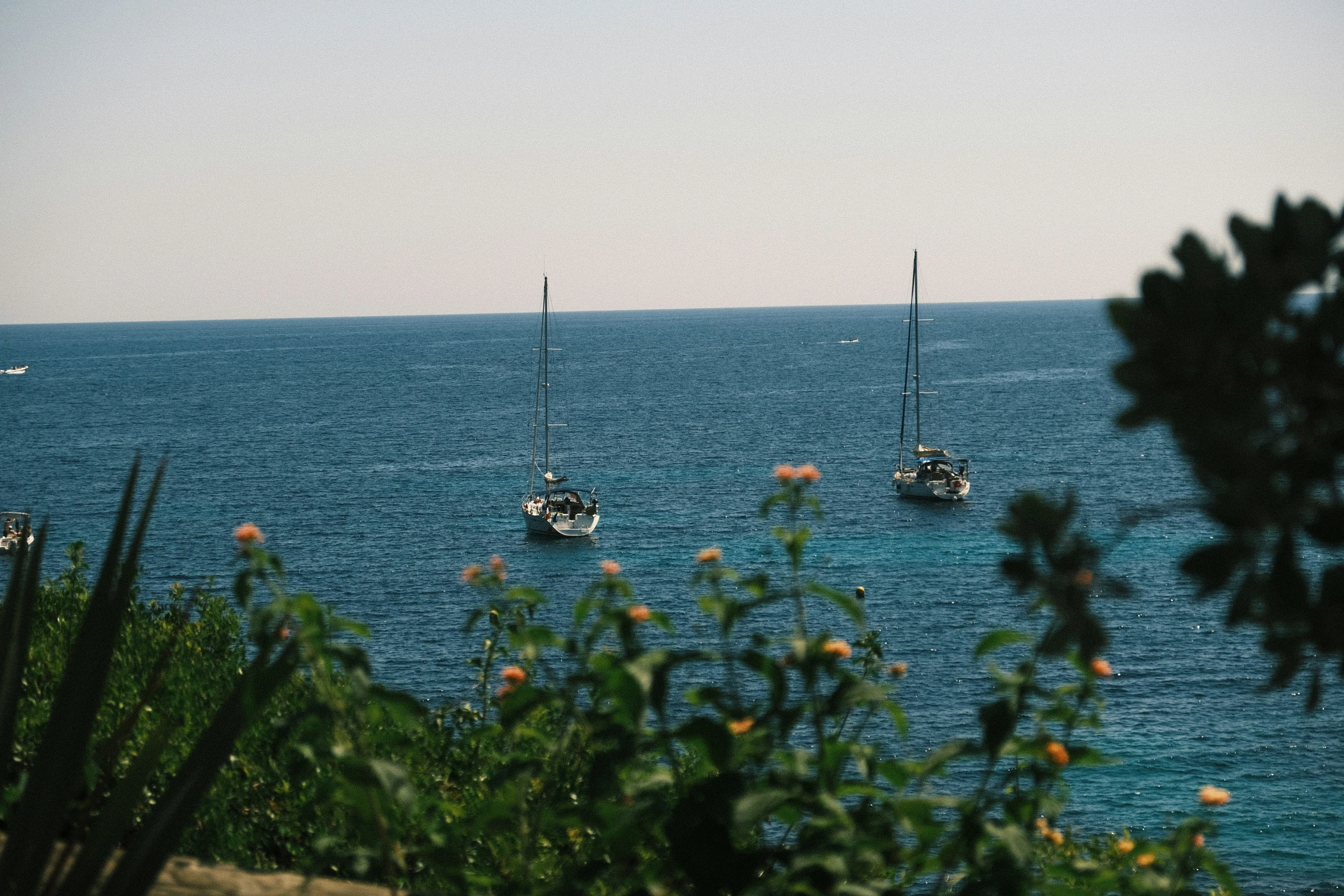 several small boats out on the ocean with clear skies