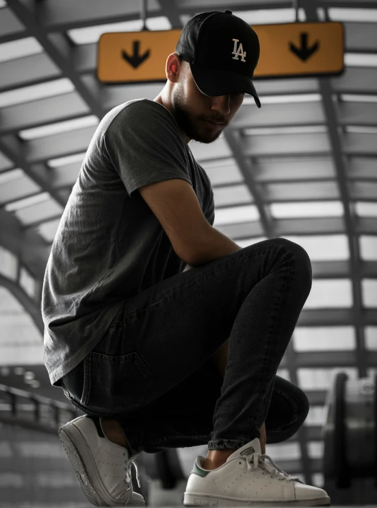 a man sitting on a bench and looking down while wearing a hat