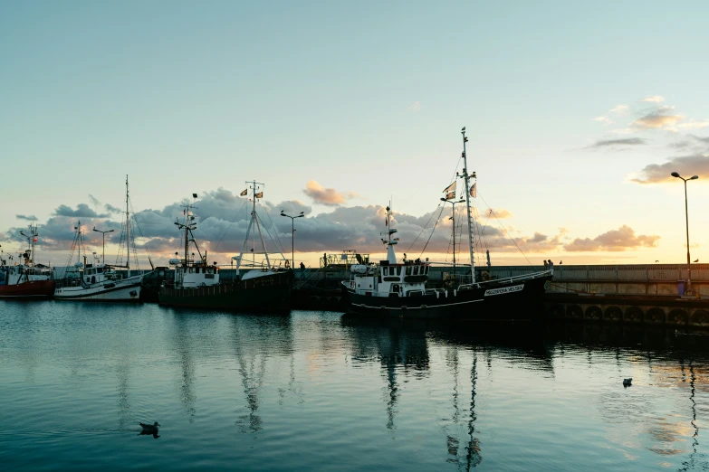 several boats parked in a small harbor at sunset