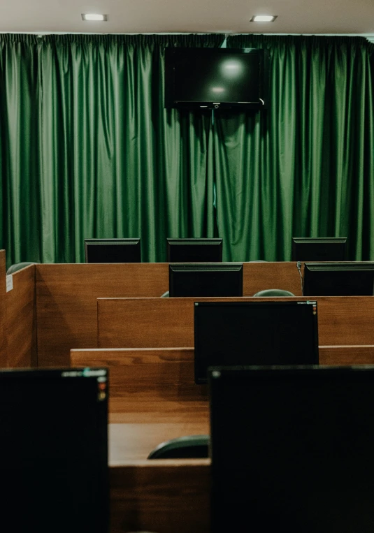 a view of rows of black chairs in front of green curtains