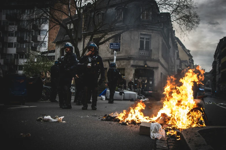 a group of police standing next to a fire in the street