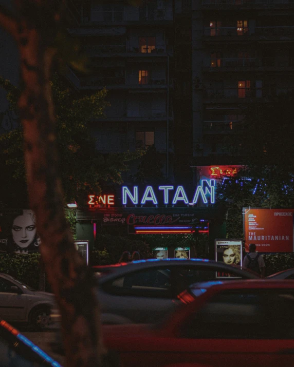 a city street at night has neon signs and buildings