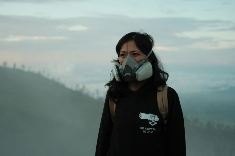 a woman standing on a hilltop wearing a mask