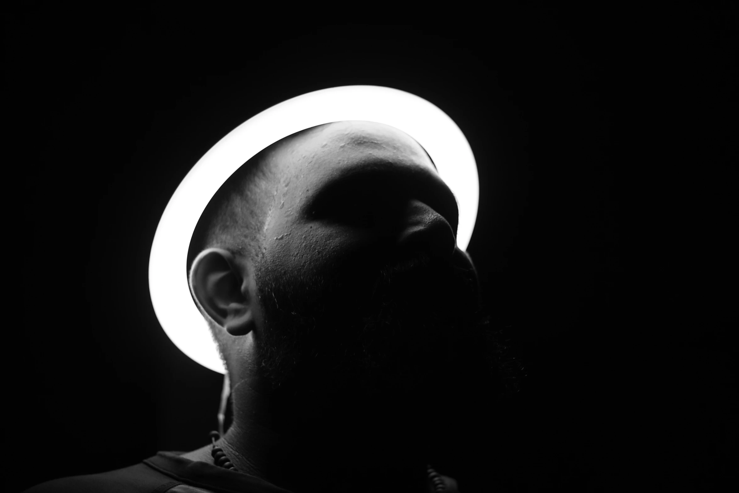 the profile of a man with an illuminated ring around his face