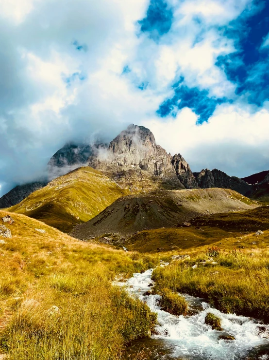 the clouds are gathering over a mountain and stream