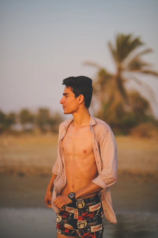 the man is shirtless on the beach while holding a phone