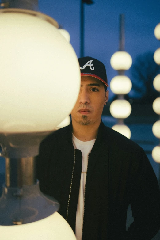 a man wearing a hat while standing in front of a lamp