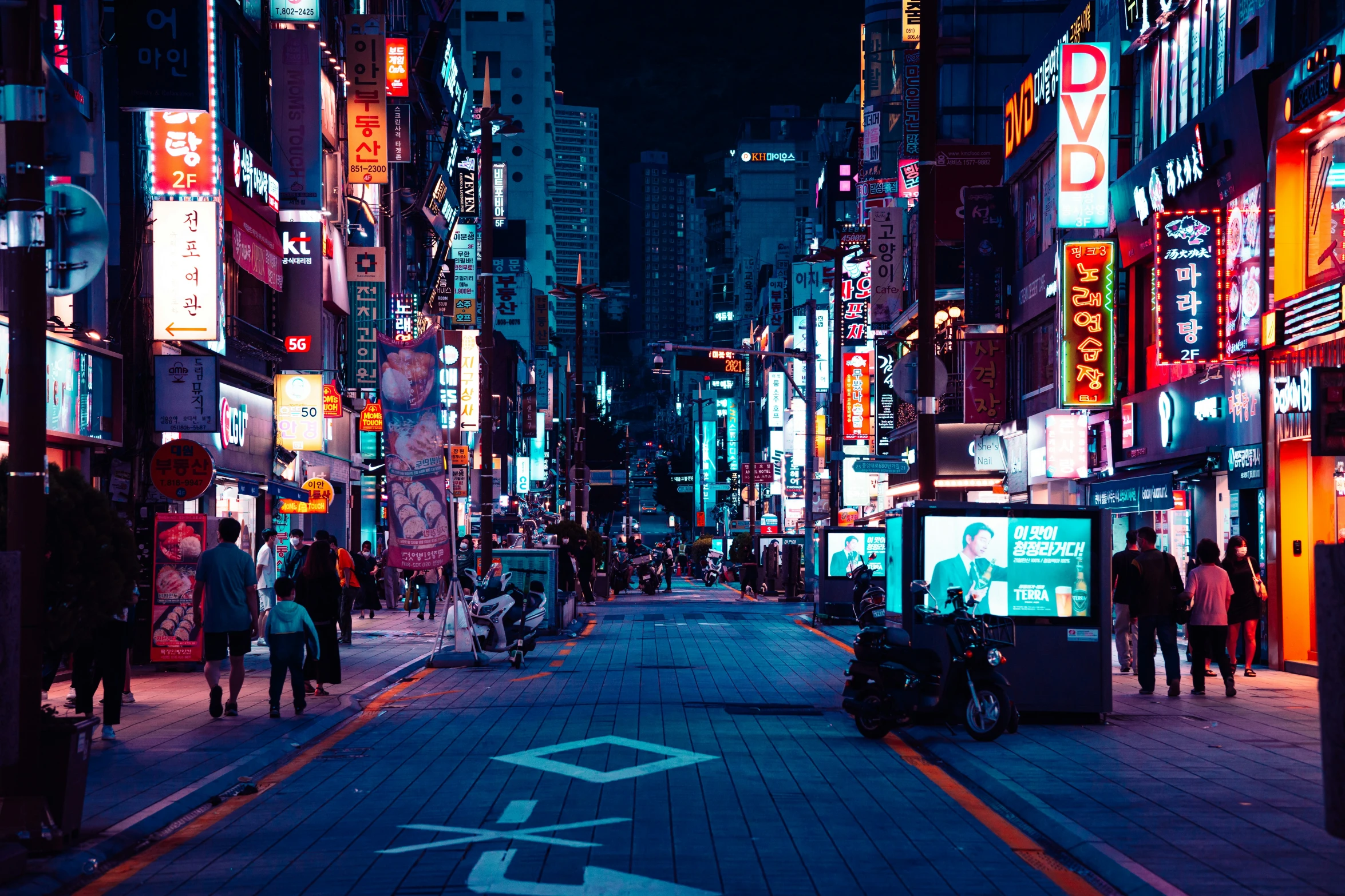 a narrow city street at night filled with neon signs