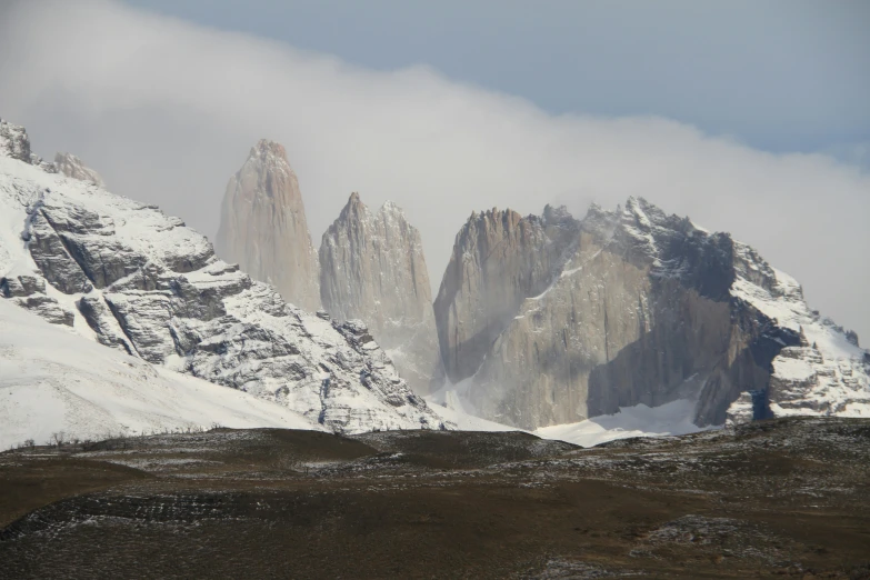 a tall snowy mountain in the background with some clouds above it