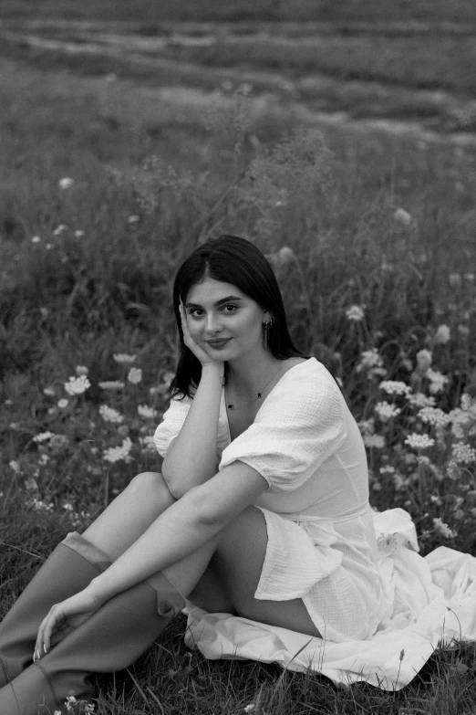 woman in white dress sitting on grass with flowers