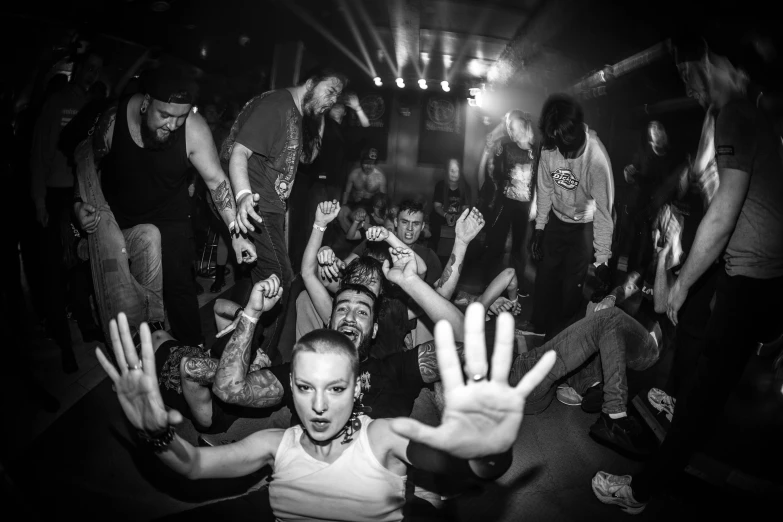 an audience at a concert, with people on either side of the stage holding up their hands