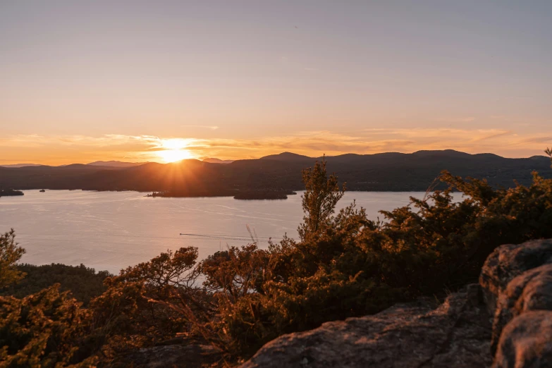 the sun setting over a bay with some mountains in the distance