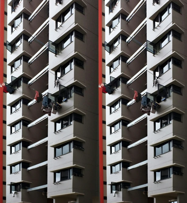 two tall brown buildings with windows and some men working on windows