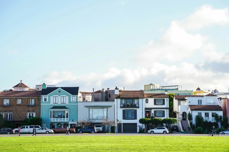 a grassy field sits near several row homes in the distance