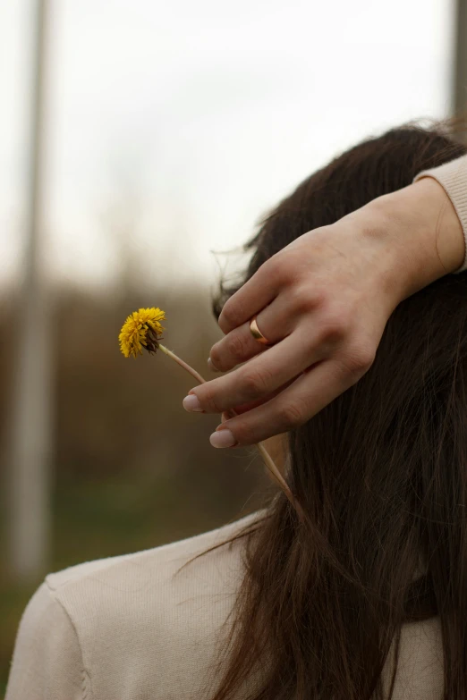 a woman's hand on the back of her head with a yellow flower