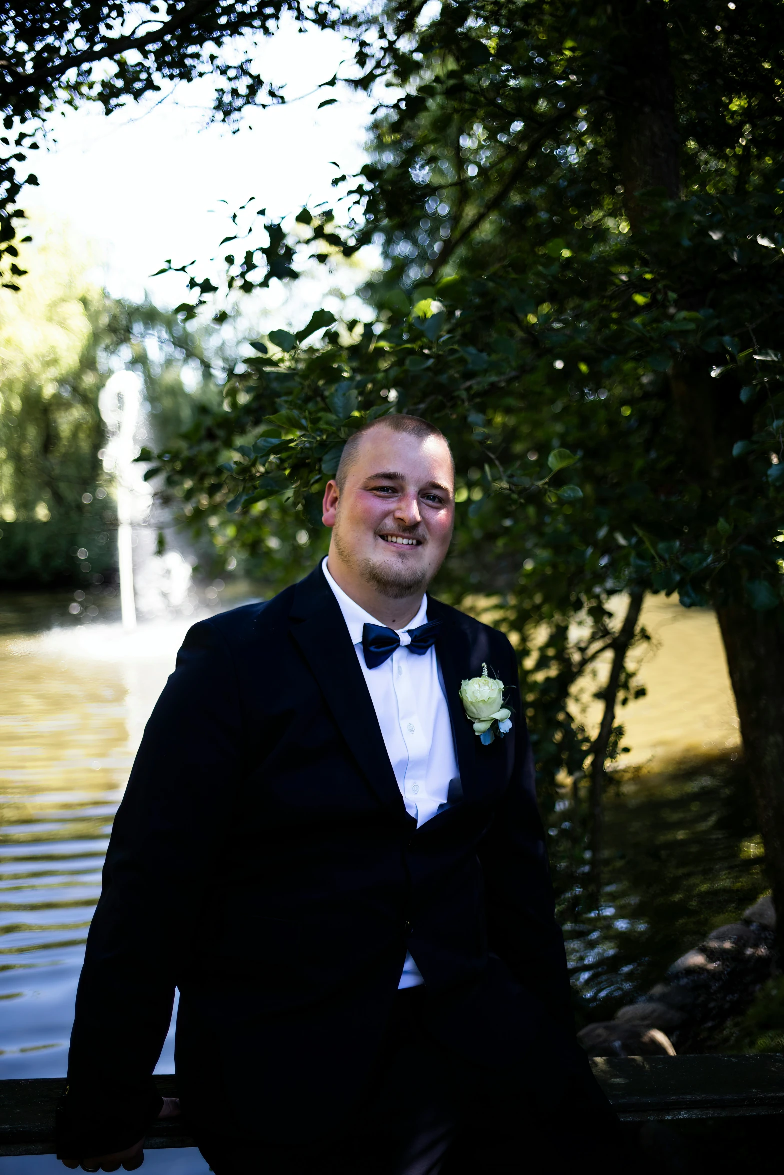 a man in tuxedo standing near a pond