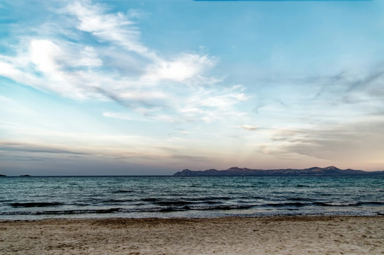 a cloudy day on the beach, as an airplane flies overhead