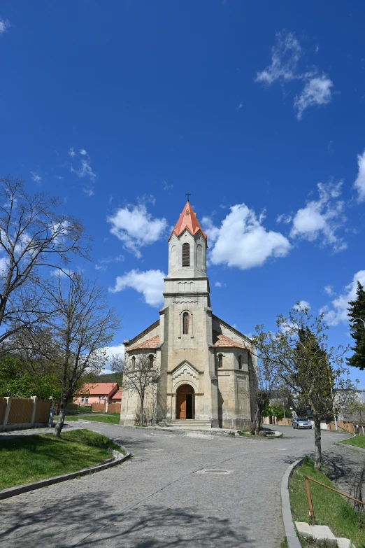 an old church with a bell tower stands among trees and a path