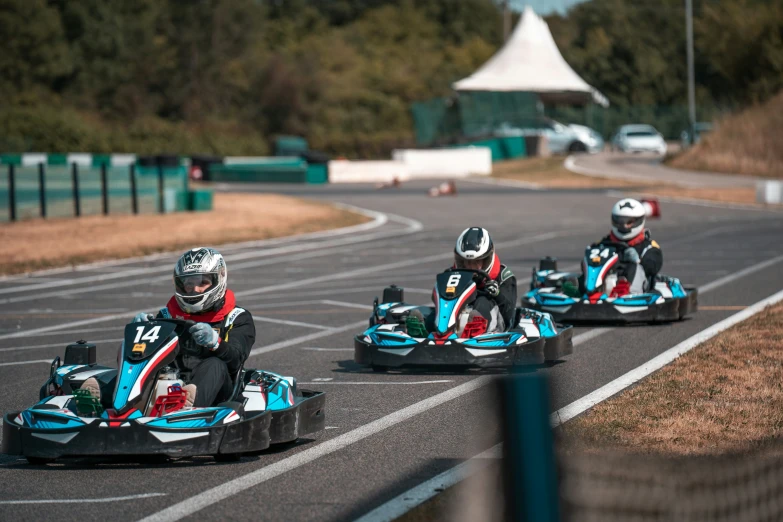 three people in go kart race cars making their way down the road