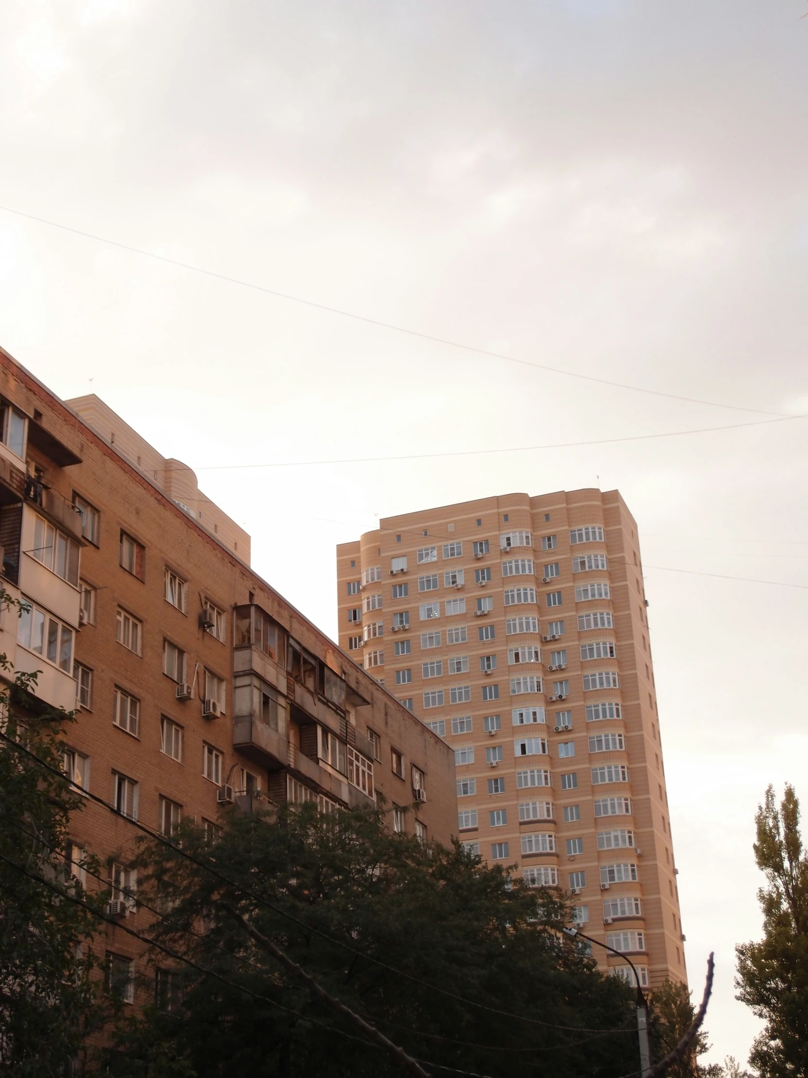 tall brown buildings with balconies and a cloudy sky