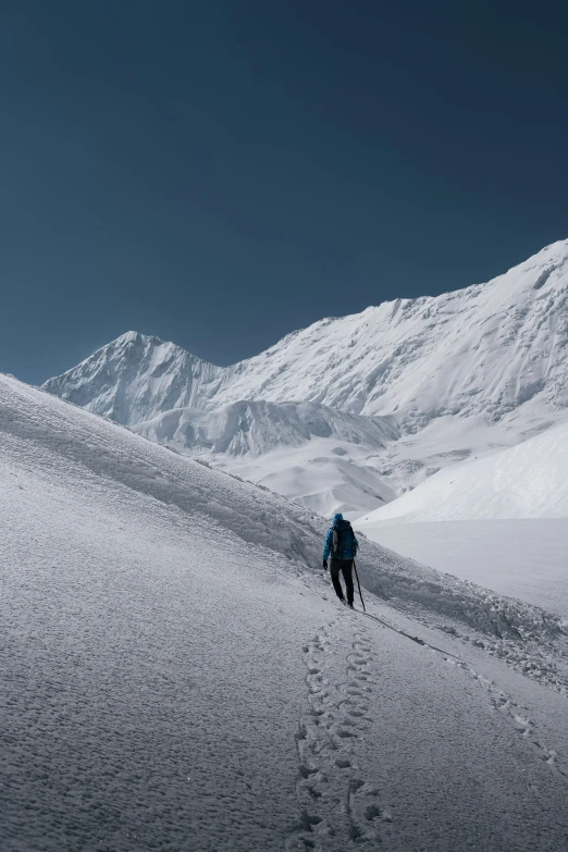 a man in a blue backpack hiking through snow covered mountains