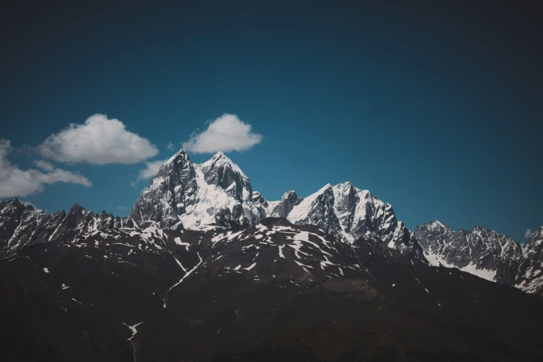 mountains covered with snow under a partly cloudy blue sky