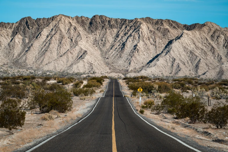 an empty road and mountains in the desert