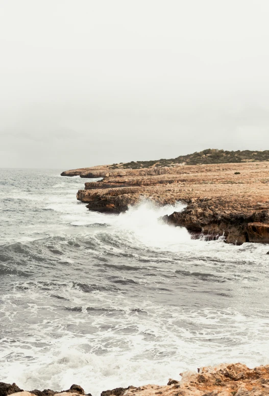 a man walking along the beach, and some waves are crashing