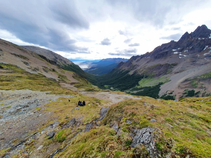 two people on a rocky path near mountain ranges