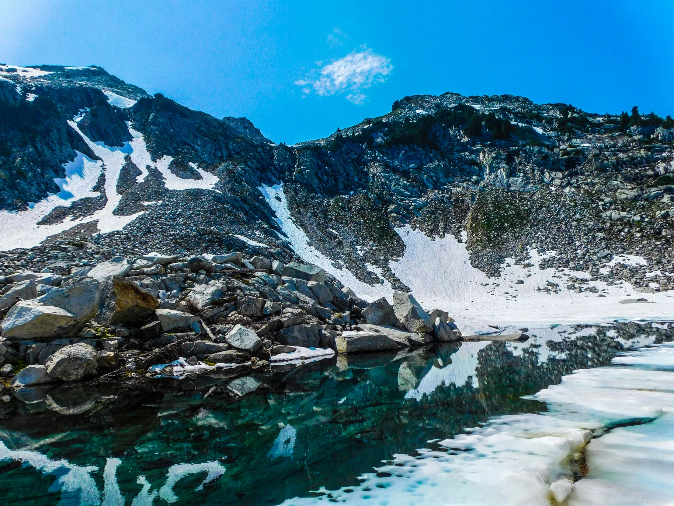 a mountain landscape with snow and some water