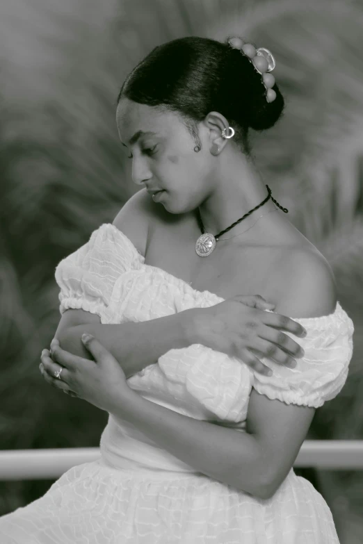 a woman in an off the shoulder dress looks down while holding her hands together