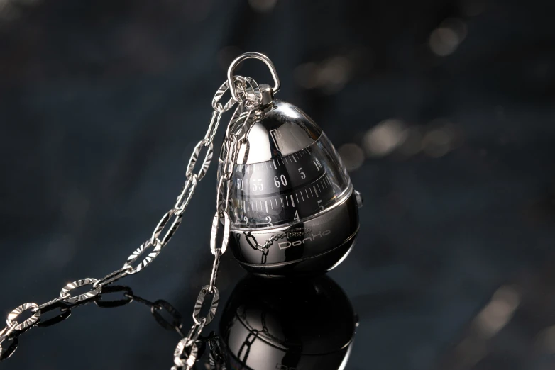 a silver ball keychain on a shiny surface