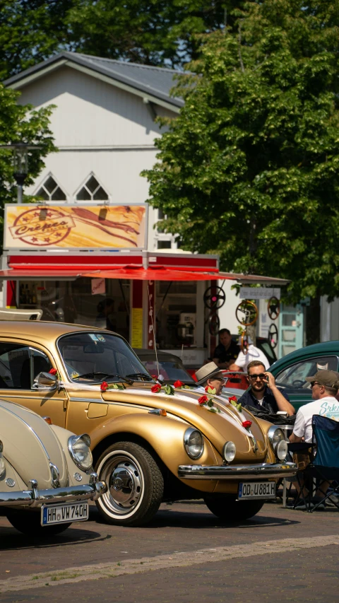 two classic cars with a gold finish on the hood, parked in a lot