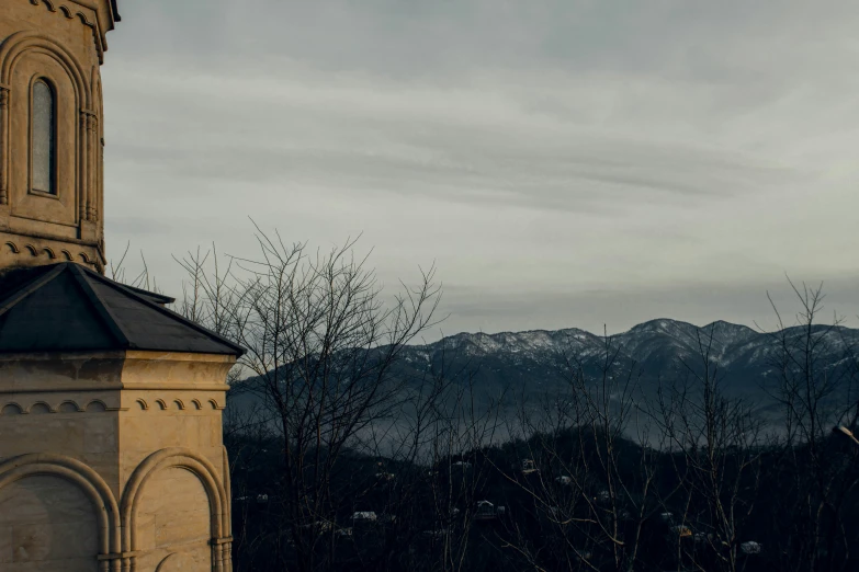 an old building with a tower on the roof, is overlooking mountains