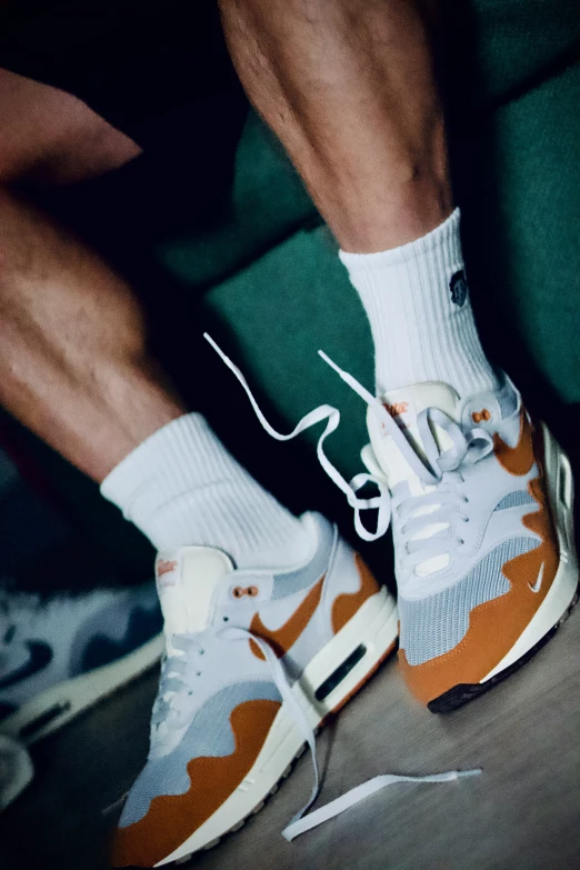 a man sitting with his foot up wearing a pair of white socks and orange camouflage print shoes