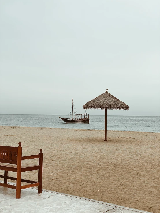 a couple of benches sitting under an umbrella on a beach