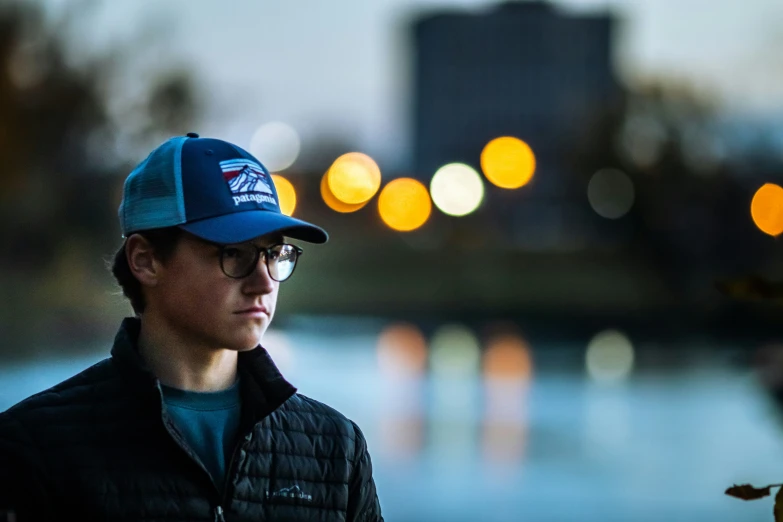 a man with glasses standing in the street wearing a hat and a jacket