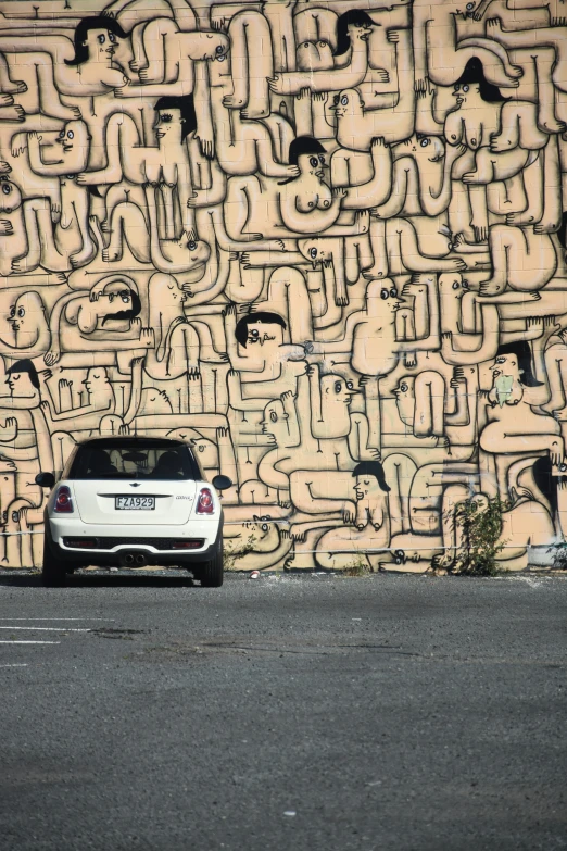 a parked white car in front of a very graffitied wall