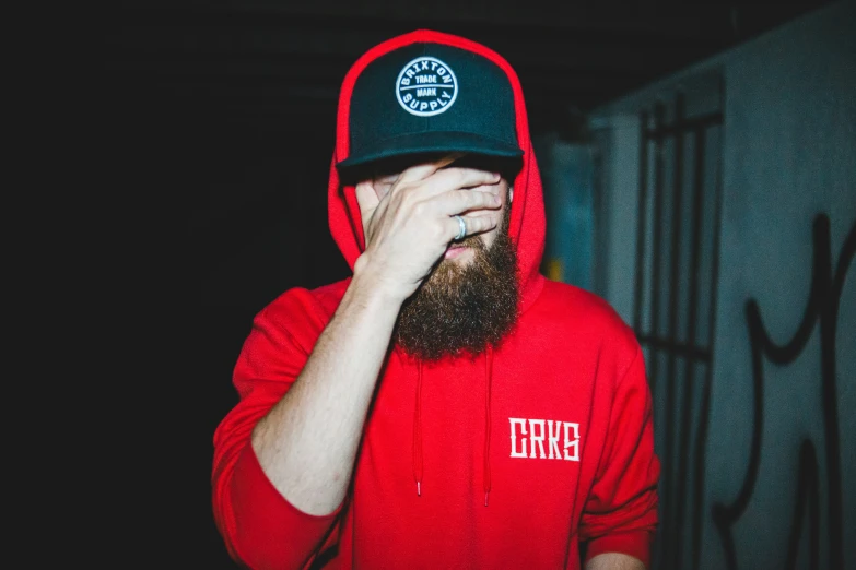 a bearded man wearing a hat and red sweatshirt