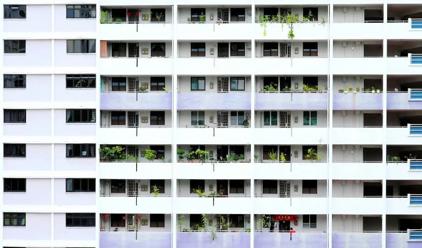 a tall white building with many windows and plants growing in them