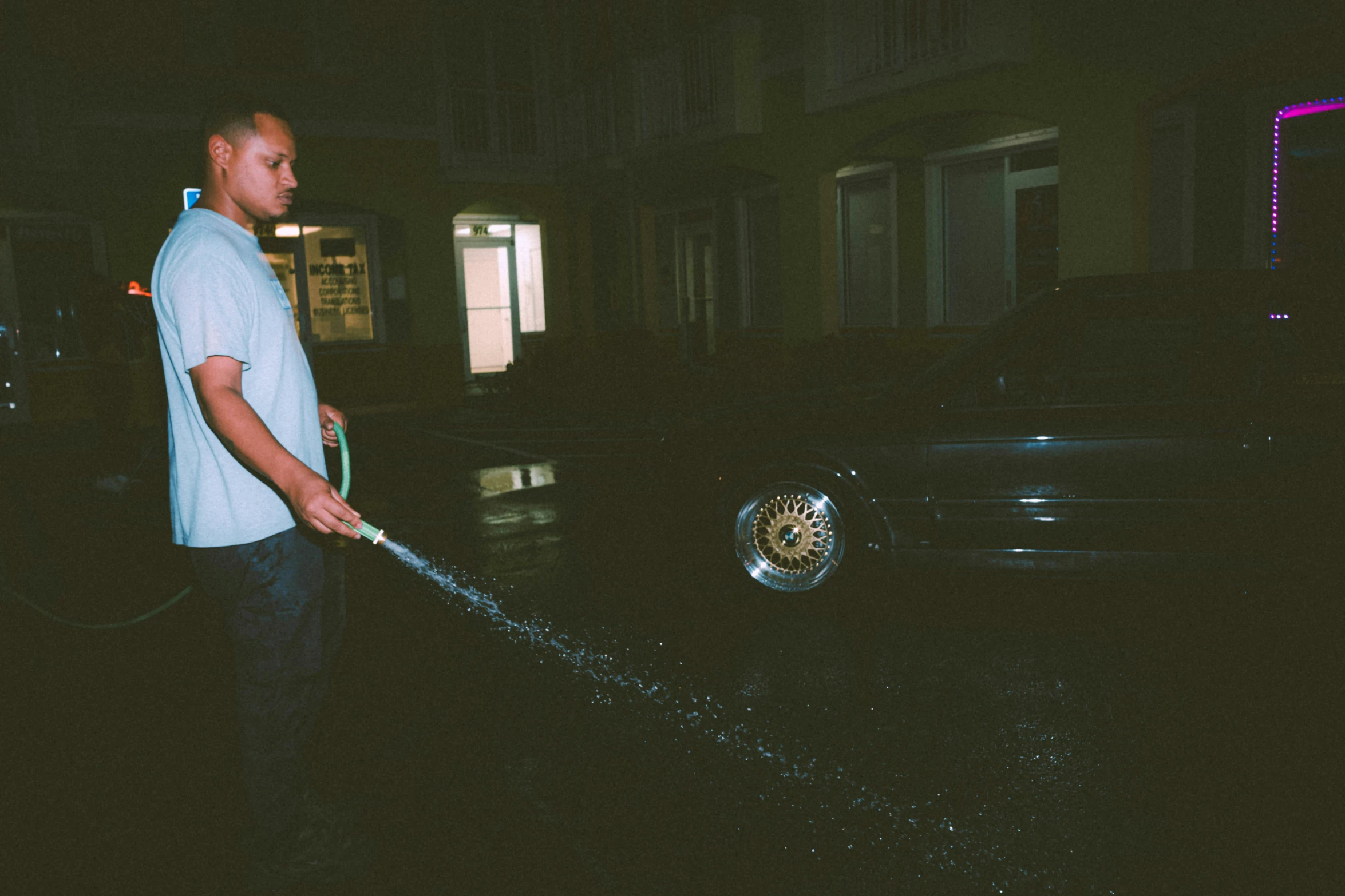 a man in blue shirt cleaning the street with a hose