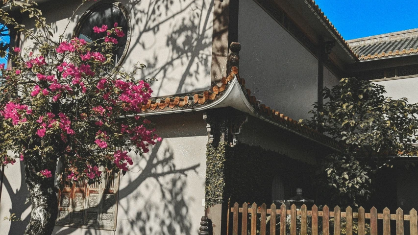 a white house with pink flowers on the outside