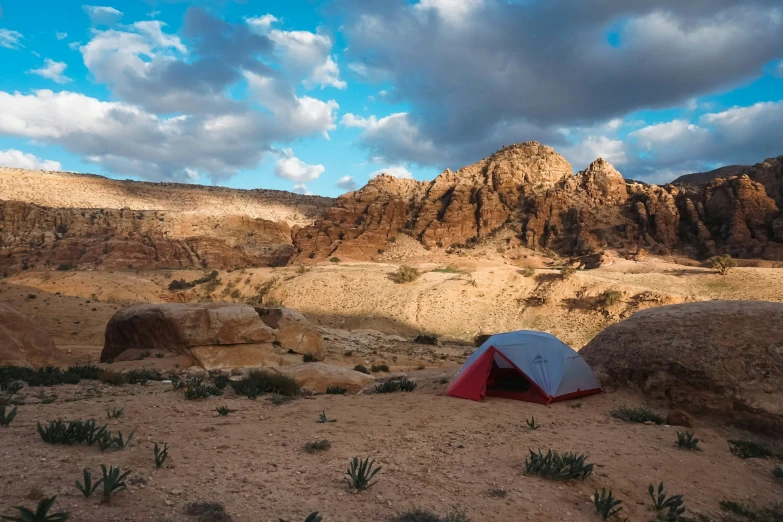 a tent on a desert with a mountain in the background